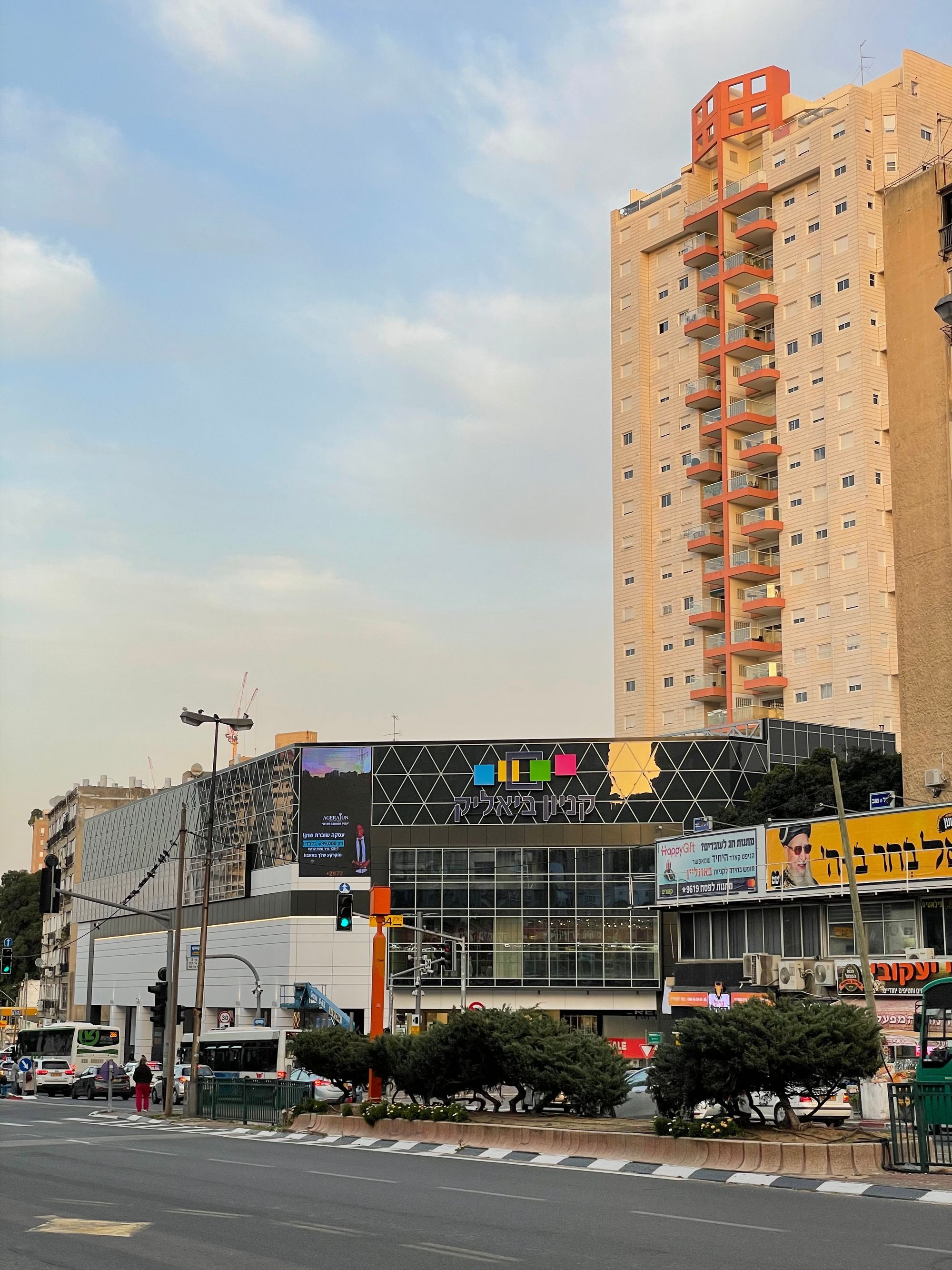 רחוב ברמת גן עם בניין מגורים גבוה ומרכז מסחרי תחת שמיים בהירים